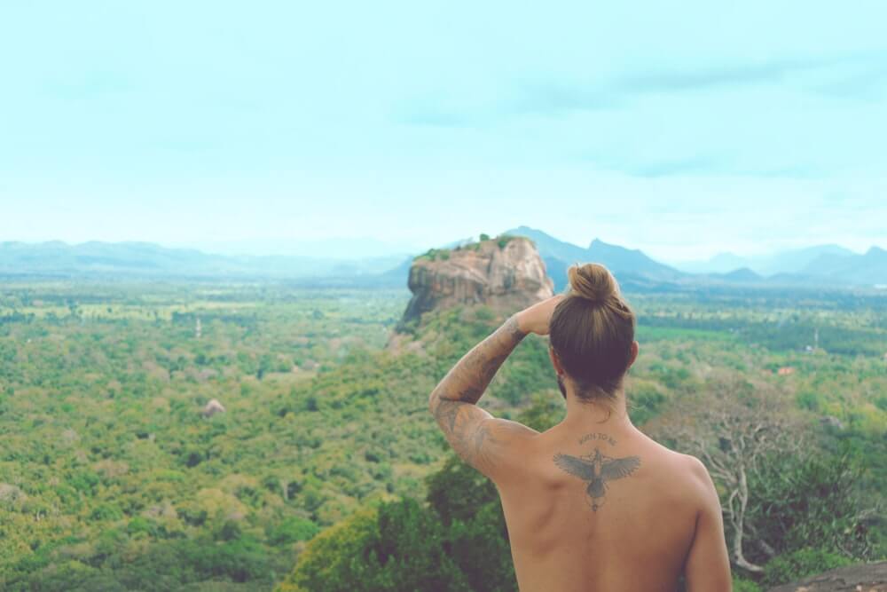 A male solo traveller stands looking out over Sigiriya in Sri Lanka