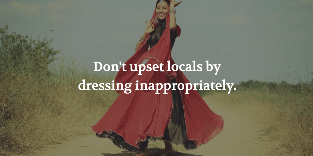 The text reads, 'Don't upset locals by dressing inappropriately.' A woman in a sari walks down a dirt road.