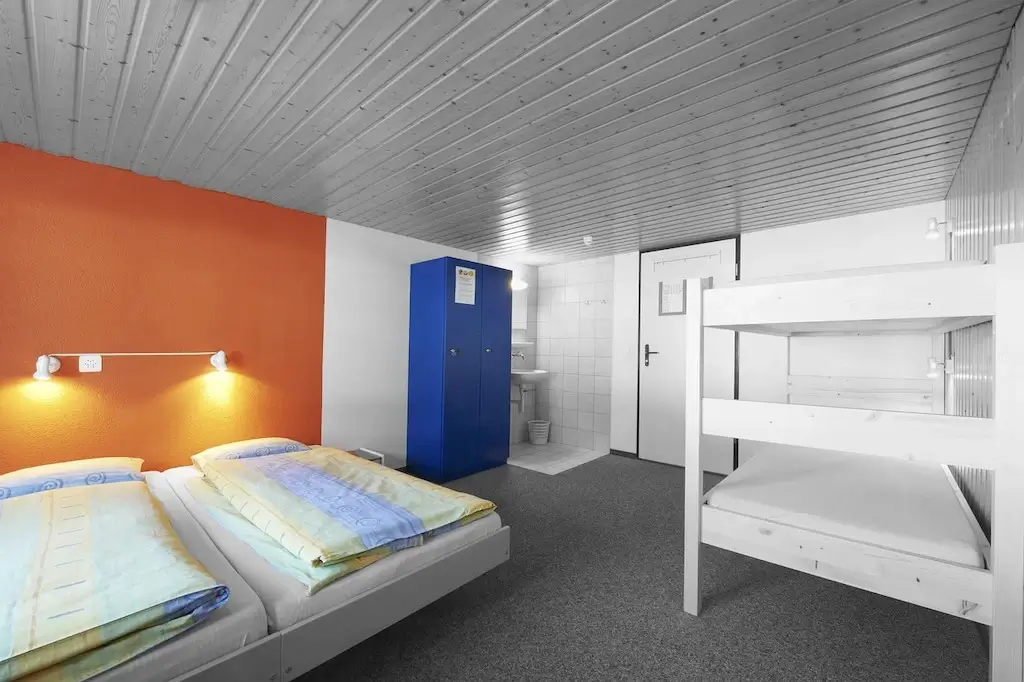 A hostel dorm room with bunk beds and a double bed.