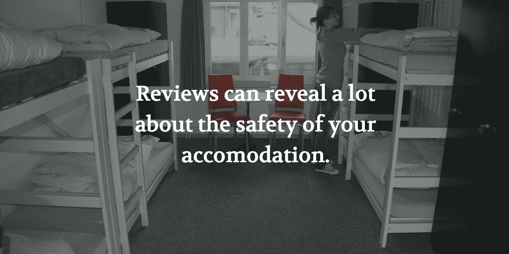 The text reads, 'Reviews can reveal a lot about the safety of your solo travel accommodation.' A women in a hostel dorm room.