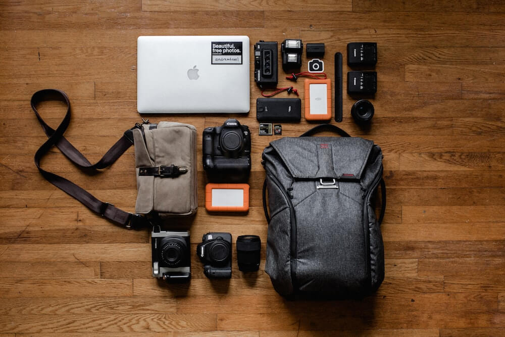 Various electronics and gadgets for clothing for travel, including a backpack, laptop and cameras.