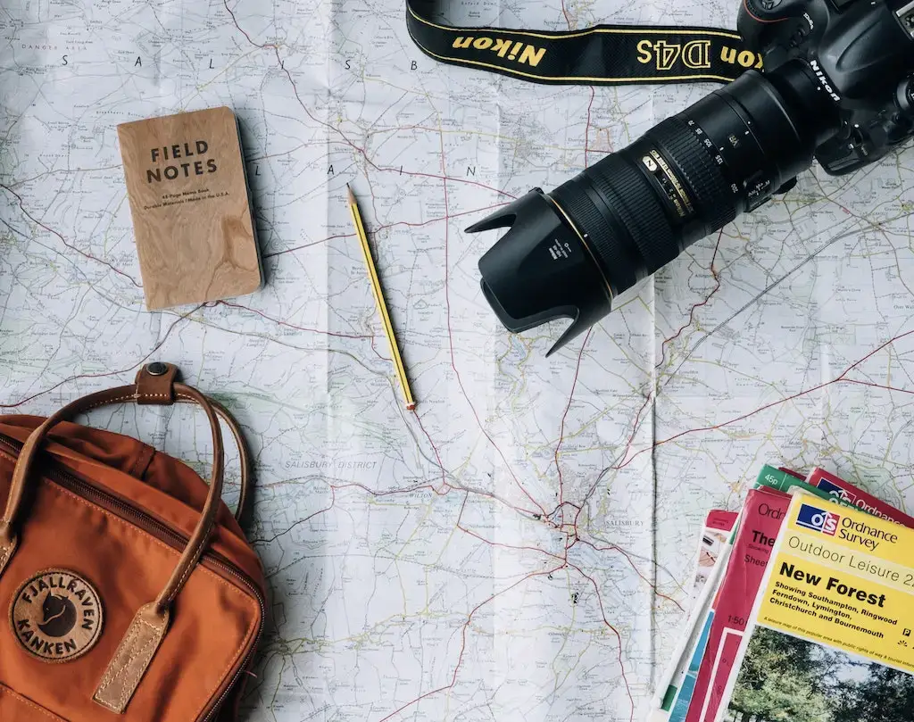 Solo travel gear including a map, backpack, camera and notebook