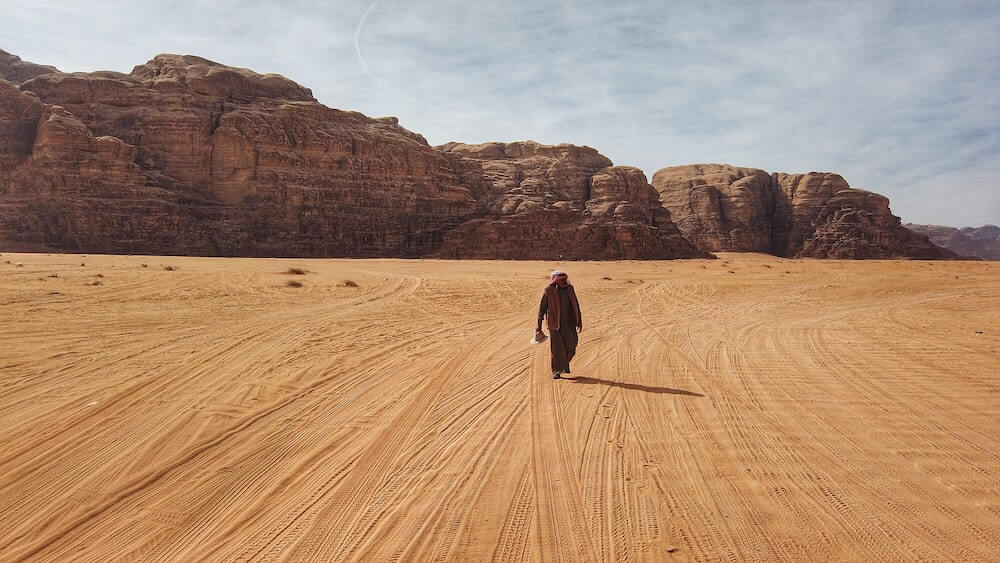 A man walks across the desert in Jordan.