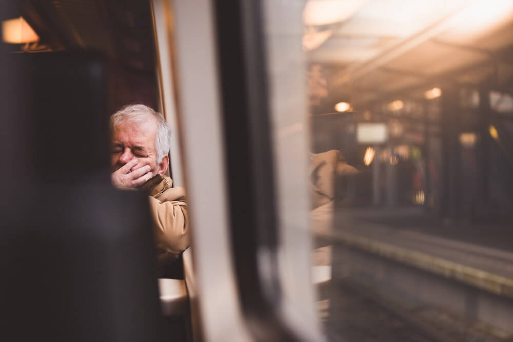A man sleeps against the window on the train.