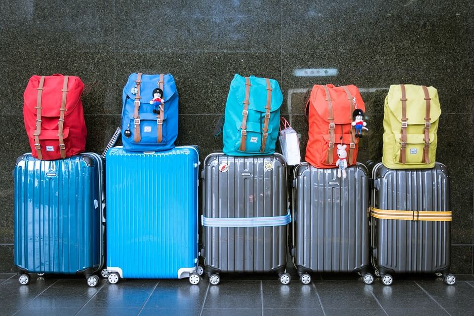 Several suitcases sitting next to each other with backpacks on top.