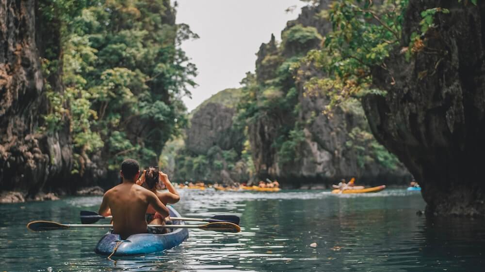 A travel couple kayak together in South East Asia.