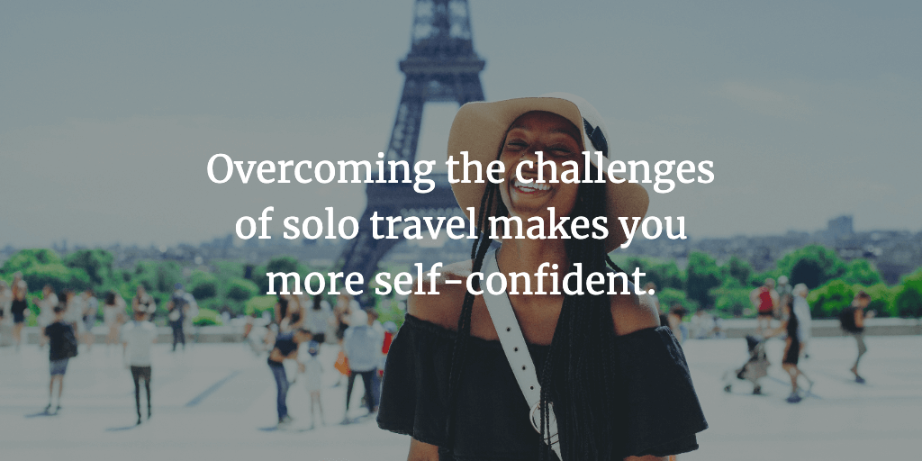 A female traveller smiles in front of the Eiffel Tower in Paris, France. The text reads, 'Overcoming the challenges of solo travel makes you more self-confident.'