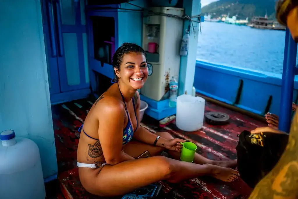 A woman travelling alone on a boat, smiling and happy