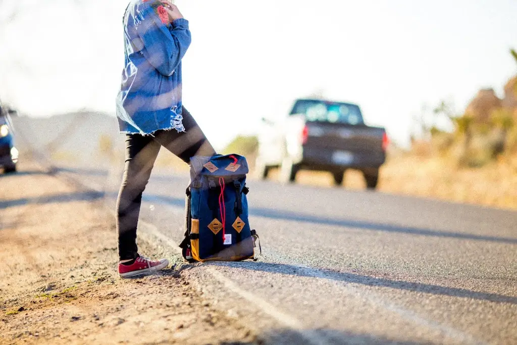 A female hitchhiker on the side of the road.