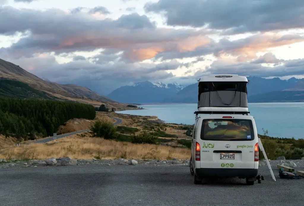A budget campervan camped on the edge of Lake Wanaka in New Zealand.
