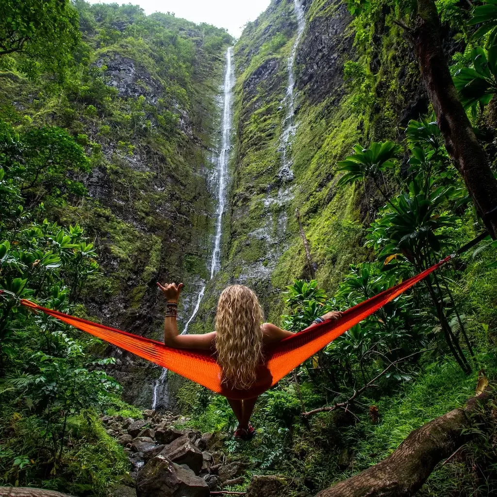 Solo female traveller in a hammock by a waterfall.