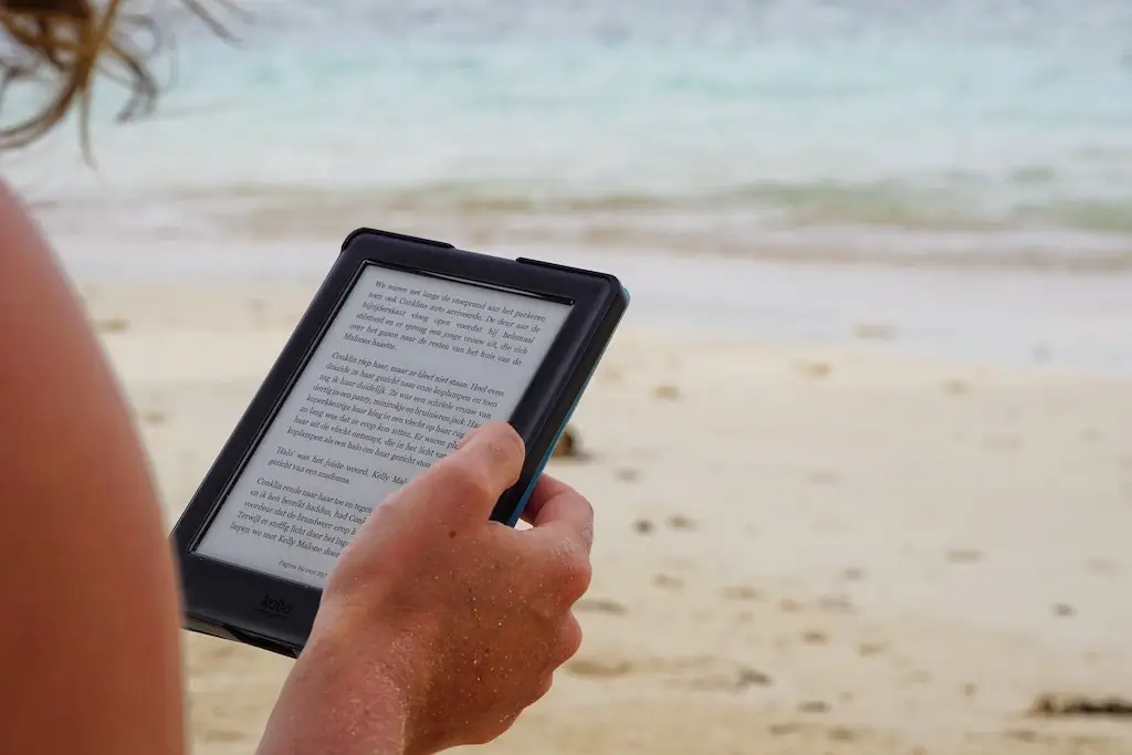 A woman reading a Kindle eReader on the beach
