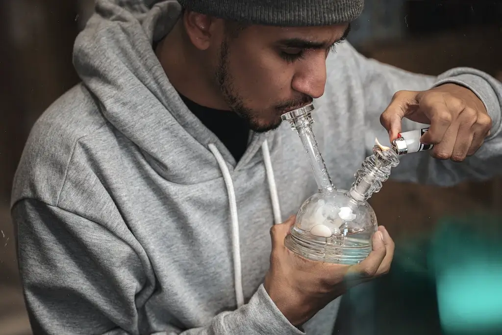 A man smoking weed through a bong bubbler.
