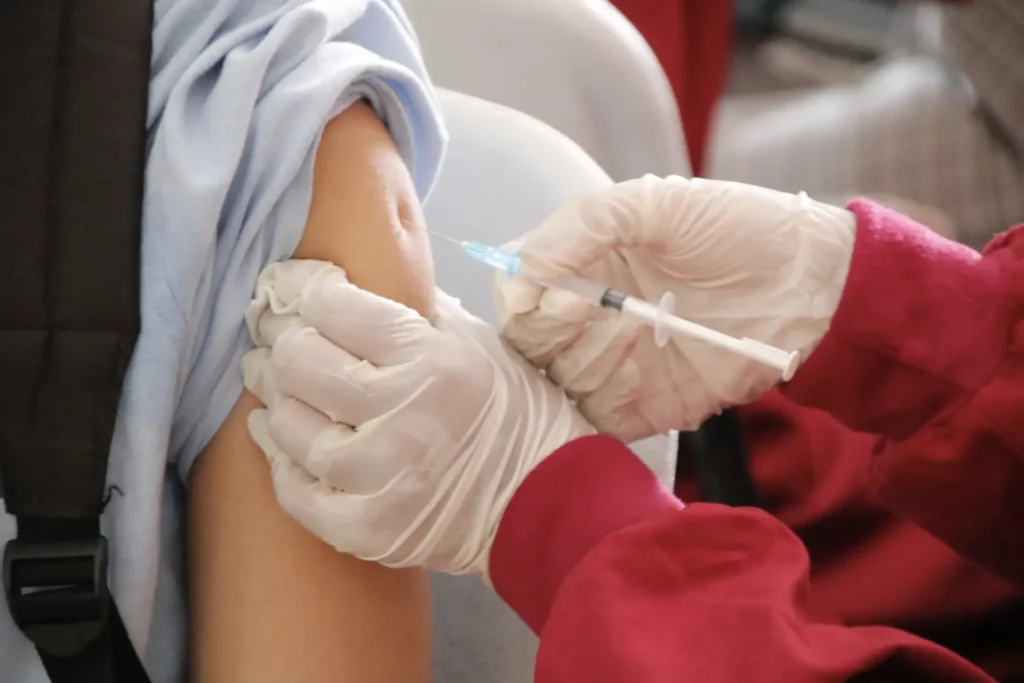 A person receiving a vaccine needle in the arm.