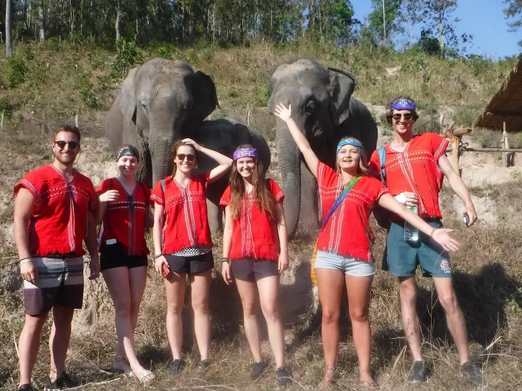 Harry (Nomadic Yak) with a group of friends and elephants in Thailand.