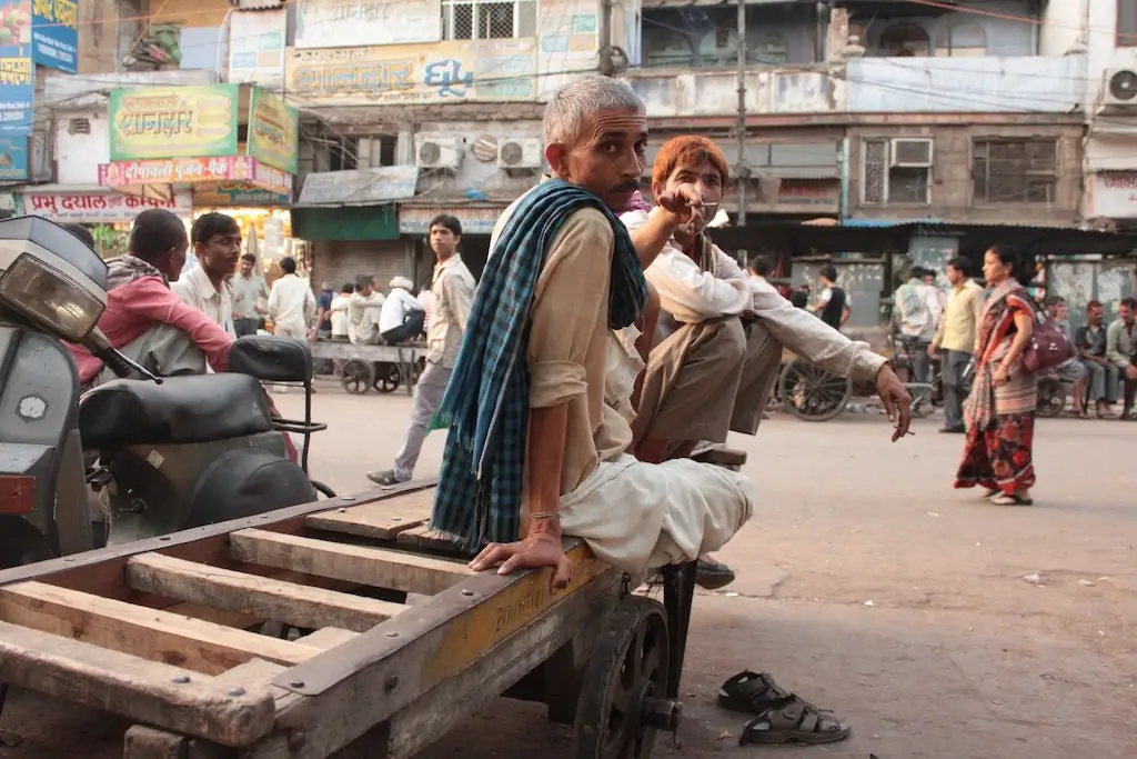 Two men smoking in a street slum in India