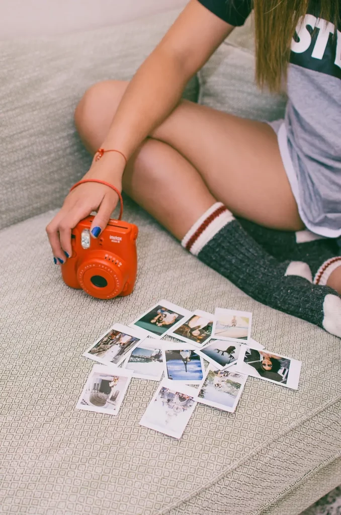 Woman sitting with her Fujifilm Instax camera and film photos.