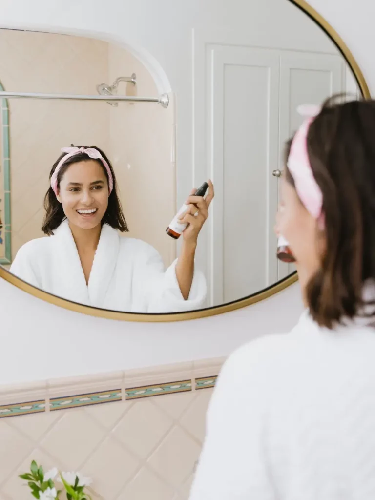 Woman pampering herself in bathroom mirror.