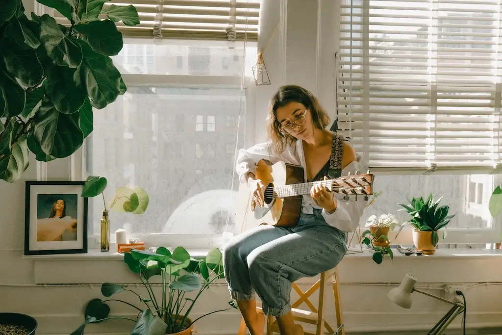 Woman playing guitar in apartment.