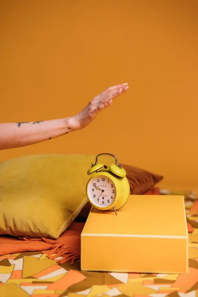 Hand slamming down on a yellow alarm clock.