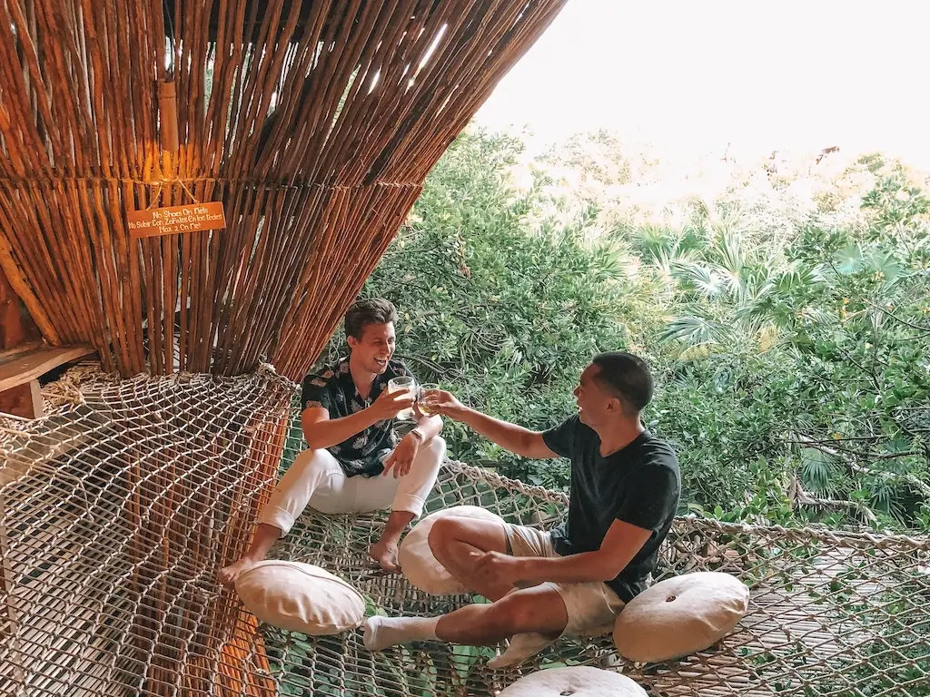 Backpackers cheersing drinks in their jungle hostel