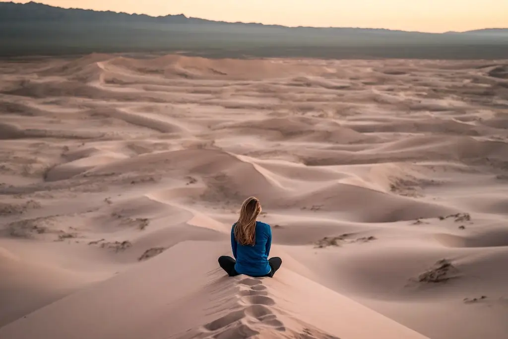 Solo female traveller meditating in the desert