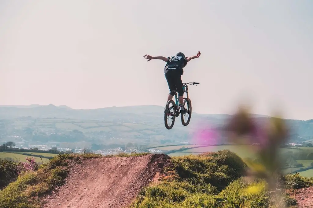Mountain biker doing a trick off of a dirt jump.