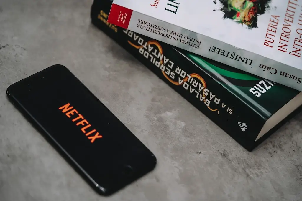 Netflix on an iPhone next to books.