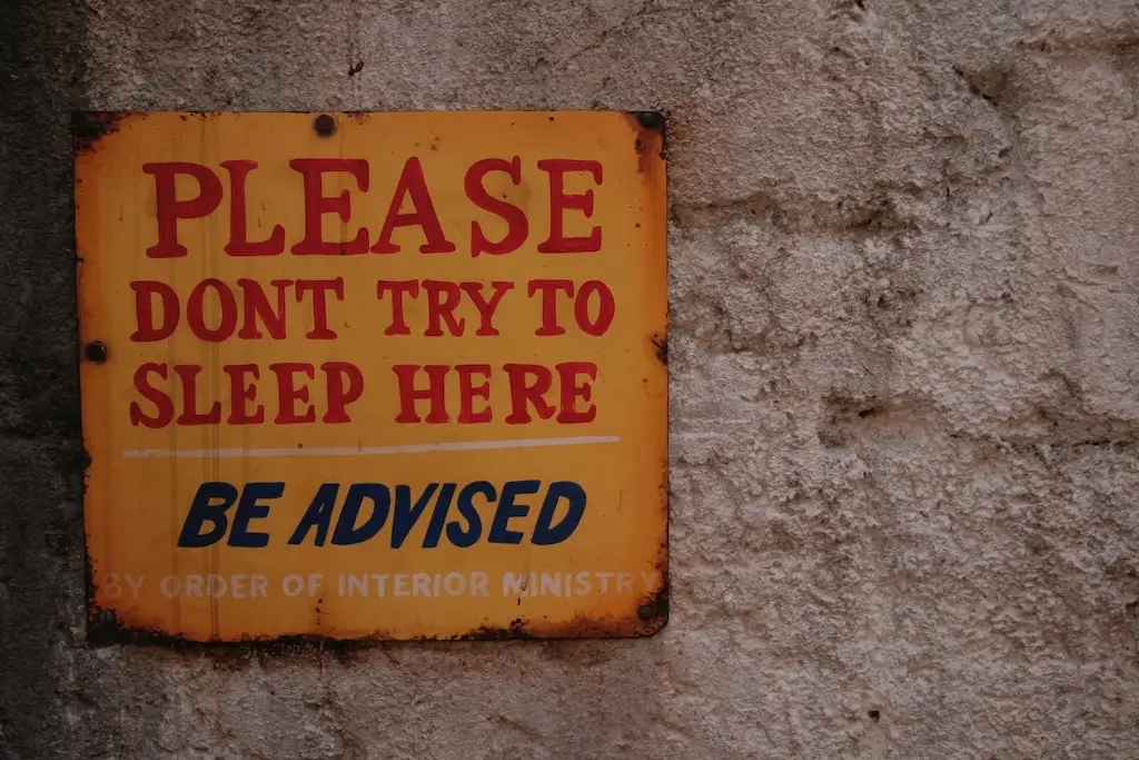 Street sign saying "Please don't try to sleep here"