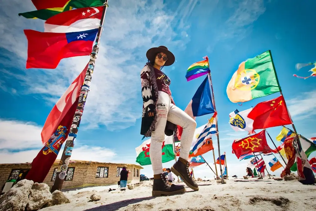 A South American female traveller standing amongst world flags.