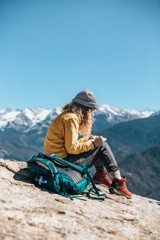 Female solo traveller journalling on a mountain.