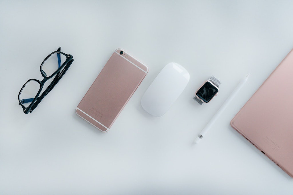 Collection of pink devices including an iPhone, Airpods, watch, Apple pencil and Macbook.