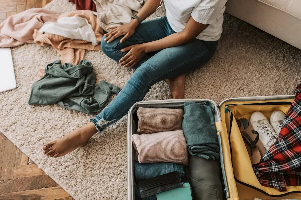 Female traveller packing her clothes and shoes into a suitcase.