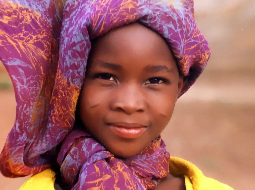 Young girl dressed in traditional clothing with facial markings in Burkina Faso. 