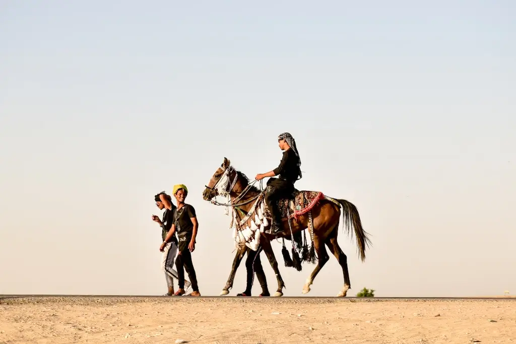 Shia Islamic man riding a horse in desert in Iraq. 
