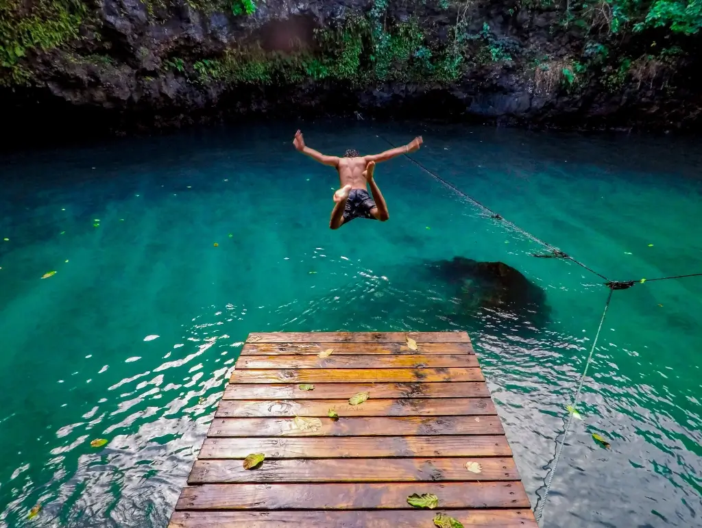 Male solo traveller diving into To Sua Ocean Trench in Samoa. 