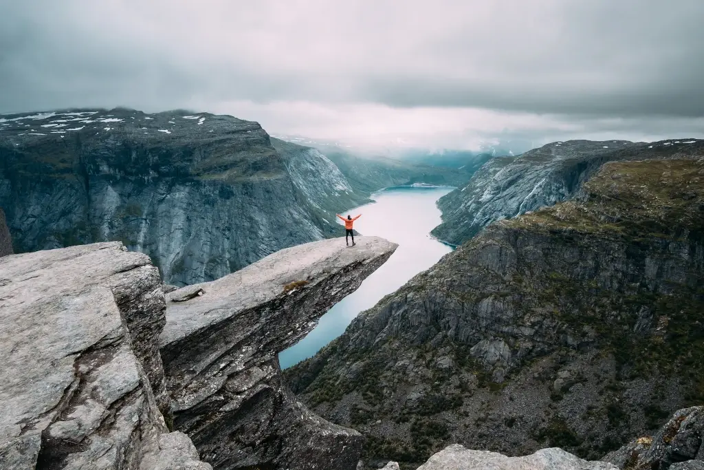 Solo backpacker sitting on the edge of Trolltunga in a fjord in Norway. 